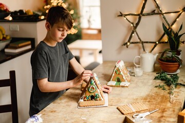 boy building and decorating a gingerbread house