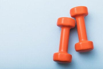 Orange dumbbells on a blue background with copy space, top view
