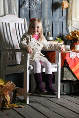 girl sitting on a chair in halloween decorations, smiling and making faces