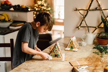 boy building and decorating a gingerbread house