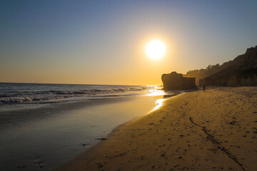 sunset at the beach with large rock formations and waves rolling in at El Matador beach in Malibu...