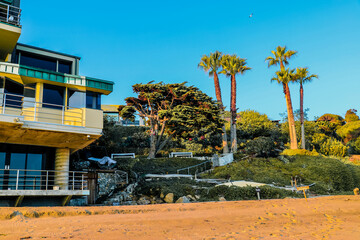 a beautiful summer landscape with a home on the beach near a lush green hillside with palm trees ...