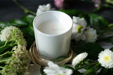 Obraz na płótnie Canvas white scented candle and delicate flowers. home fragrances for relaxation and calm. flower fragrance for home. unbranded ceramic candle.