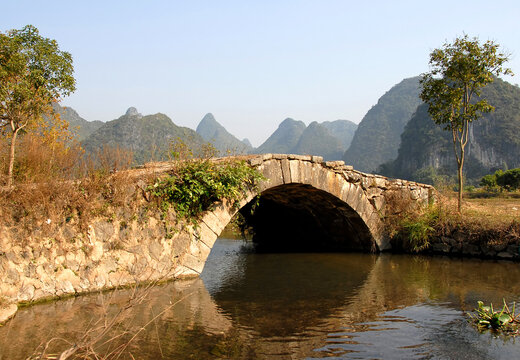 Scenery along the Yulong River near Yangshuo, Guilin in Guangxi Province, China. An ancient stone bridge near Yangshuo. The old bridge crosses a stream connecting farmland near to the Yulong River.