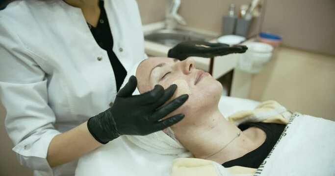 4k Slow motion. Female cosmetologist applying cosmetic treatment on client's face at the cosmetology clinic