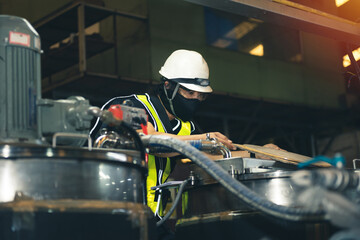 Obraz premium Technician engineer mechanic with mask worker in safety white helmet and vest working or checking machine at factory.