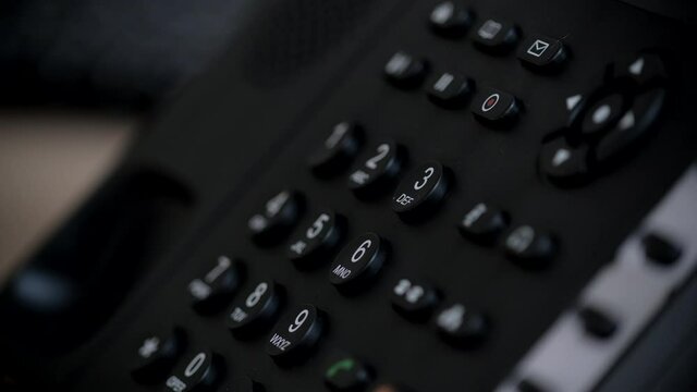 Office worker uses a landline phone to answer incoming calls and dialing a number to make a call. Businesswoman picking up the phone to answer a phone call. Close-up of women's hands with a phone