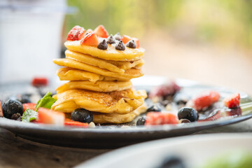 Delicious homemade pancakes with summer berries, Strawberry fruit and Chocolate Chip for breakfast. Morning meal pancakes topped with honey on dish.