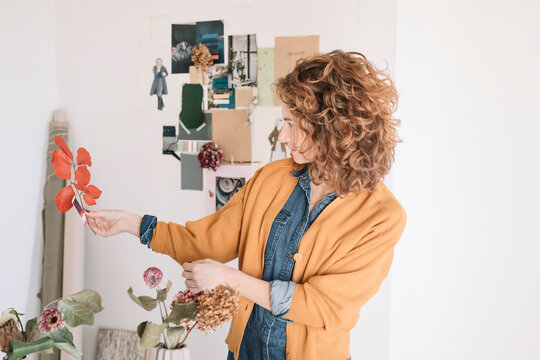 Young Woman Selecting And Hanging Flowers For Moodboard