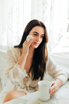 Young woman cleaning her face with beauty product
