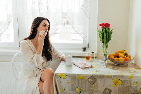 Young woman cleaning her face with beauty product