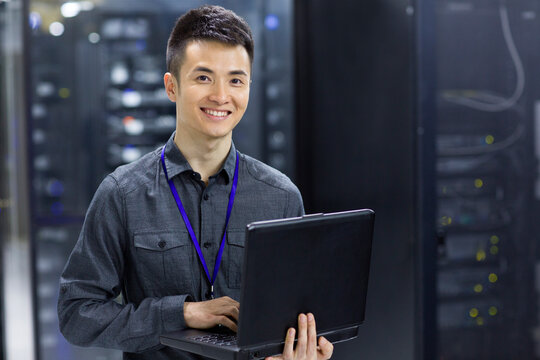 Technician using laptop in computer room