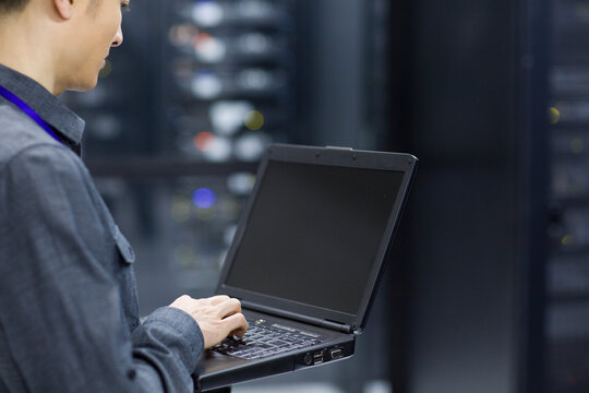 Technician using laptop in computer room