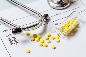 Medical concept. Yellow pills with stethoscope, pills, notepad, medical prescription on the doctor's desktop. Treating a patient in a hospital with medication.