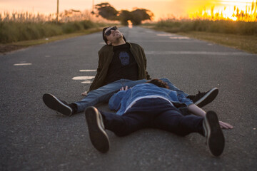 young man sitting on the road with a friend trying to reach, concept of friendship fun, travel campaign, social media advertising