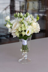 Wedding bouquet of white flowers is in a glass vase