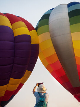 Woman tourist takes pictures of flying balloons on the phone