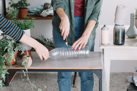 Woman Cutting Recycled Plastic Bottle To Diy A Vase