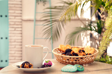 cup of coffee, hand painted stones, with pastries in wicker basket, and Mediterranean house background