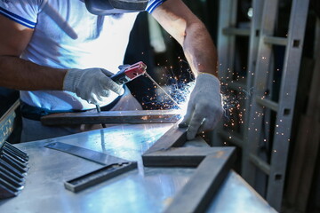 worker welds metal with electric welding