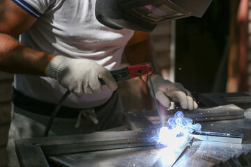 worker welds metal with electric welding