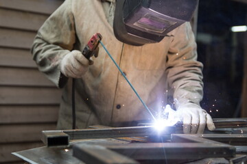 worker welds metal with electric welding