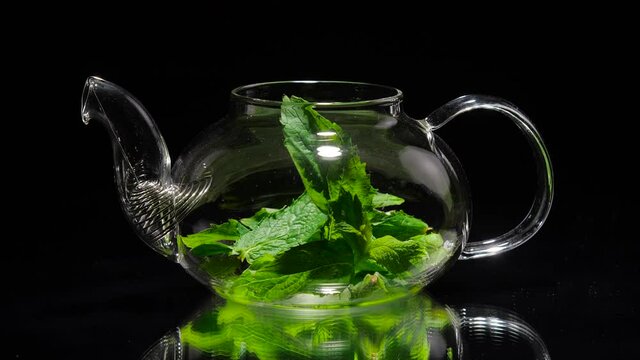 Teapot herbal tea with mint on a black background