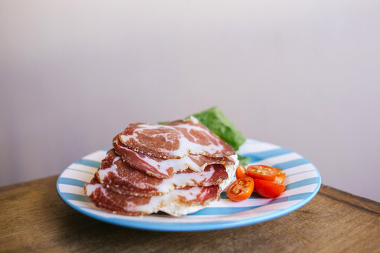 Rodajas de bondiola de cerdo en plato con r&uacute;cula y tomate cherry
