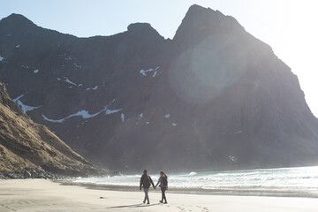 A couple walks on Kvalvika beach in Lofoten. 