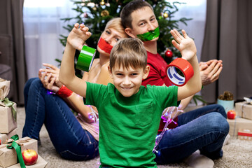 Parents with a charming seven-year-old son fool around celebrating Christmas and new year. Humor,...