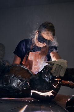 Female artist welding a sculpture.