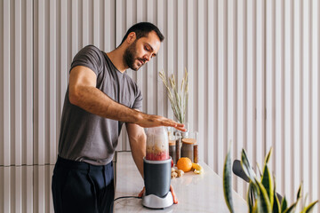 Young man making smoothie in the kitchen