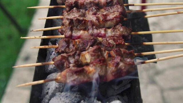 Arrosticini on the grill cooked while turning. Adult sheep meat, typical of Abruzzo region, Italy