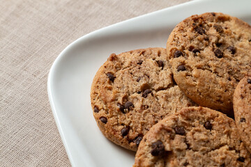Home made chocolate cookies are in a white plate on the table