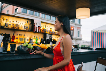 Cheerful woman in red dress sitting at bar counter