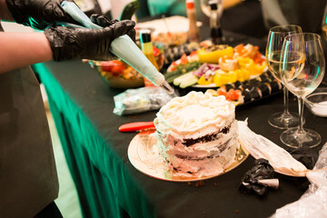 woman adorns cake with cream