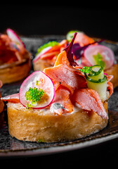 Tasty bruschetta with salmon, cucumber and cream cheese in plate