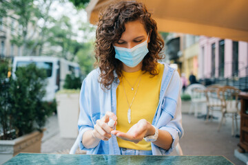 Portrait happy young woman wearing protective medical mask spraying alcohol sanitizer