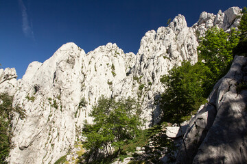 Hiking Velebit mountain in Croatia in summer, Velebit peaks Visibaba Kiza, Bacic kuk mountain rocks at Dabarski kukovi