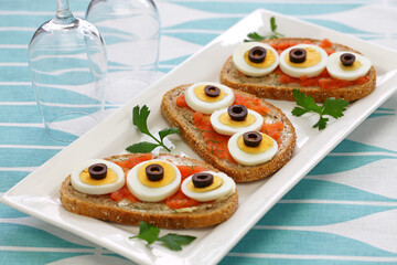 Swedish Open Sandwich with sliced boiled egg, black olives and dill on top of seasoned cod roe rye bread.

