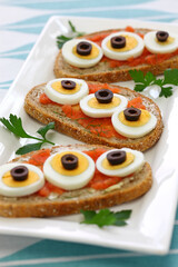 Swedish Open Sandwich with sliced boiled egg, black olives and dill on top of seasoned cod roe rye bread.
