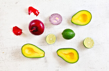 Avocado halves, limes and onions - basic guacamole ingredients on white working board, flat lay photo