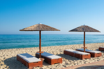 Sun Beds with shades covering from the hot summer sun in Ikaria beach, Greece