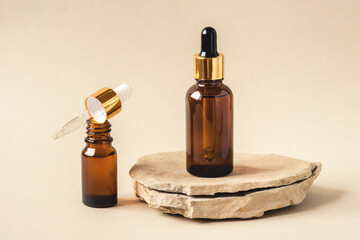 Two brown bottles of cosmetics on a natural beige background. Stone podium. Front view.