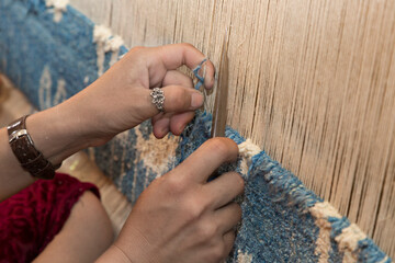 Woman hands weaving carpet on the loom, in Margilan, Uzbekistan.
