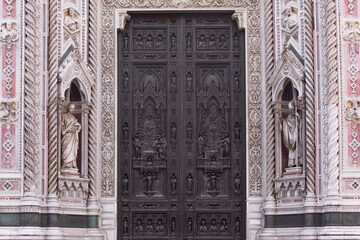 Close-up of ornate carved door, entrance to Duomo Santa Maria del Fiore, (Cathedral of Saint Mary of the Flower). Detail of facade of cathedral Florence, Italy
