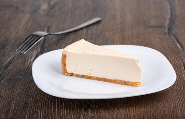 Slice of New York style cheesecake on a white plate.