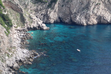 scogliera dell'isola di Capri a picco sul mare cristallino con piccola barca