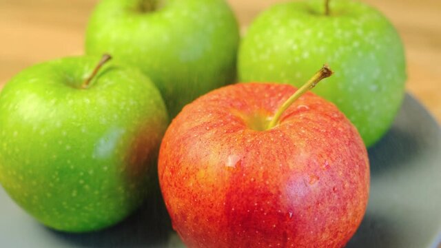 Fresh, juicy red and green apples are sprayed with water.