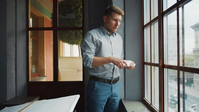 Young businessman drinking coffee by the window